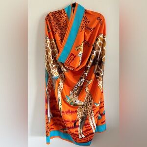 This Giraffe scarf is designed in orange, brown, and several other colors.